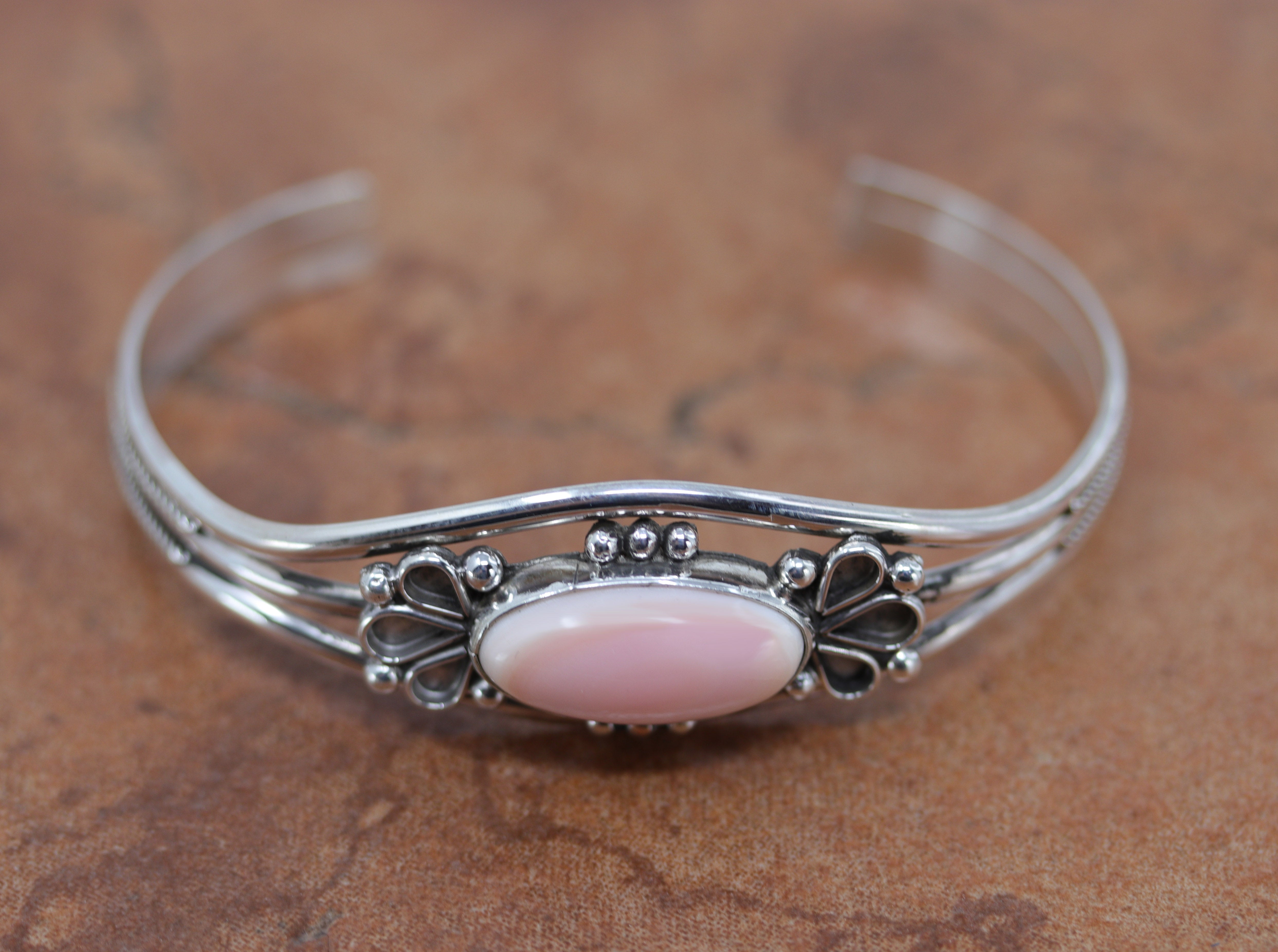 A beautiful Navajo Native American bracelet. It is made from sterling silver and pink quartz. It is about 5 1/2" around and 7/8" wide. The opening is about 1 1/4", and partly flexible.