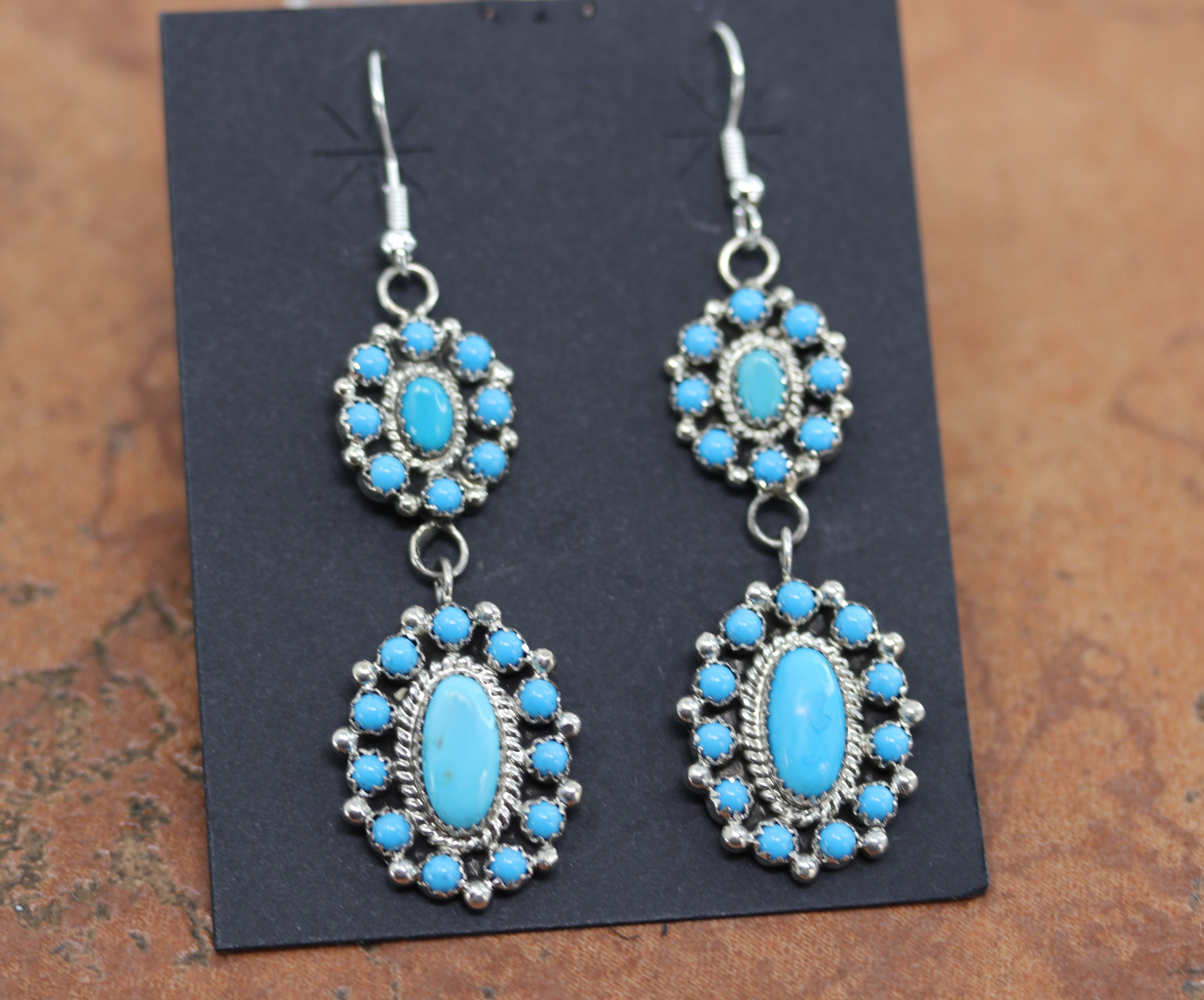 Authentic Native American cluster earrings. They are made from sterling silver and man made turquoise. The earrings are about 2 7/8" in length including the hook and 7/8" in width.