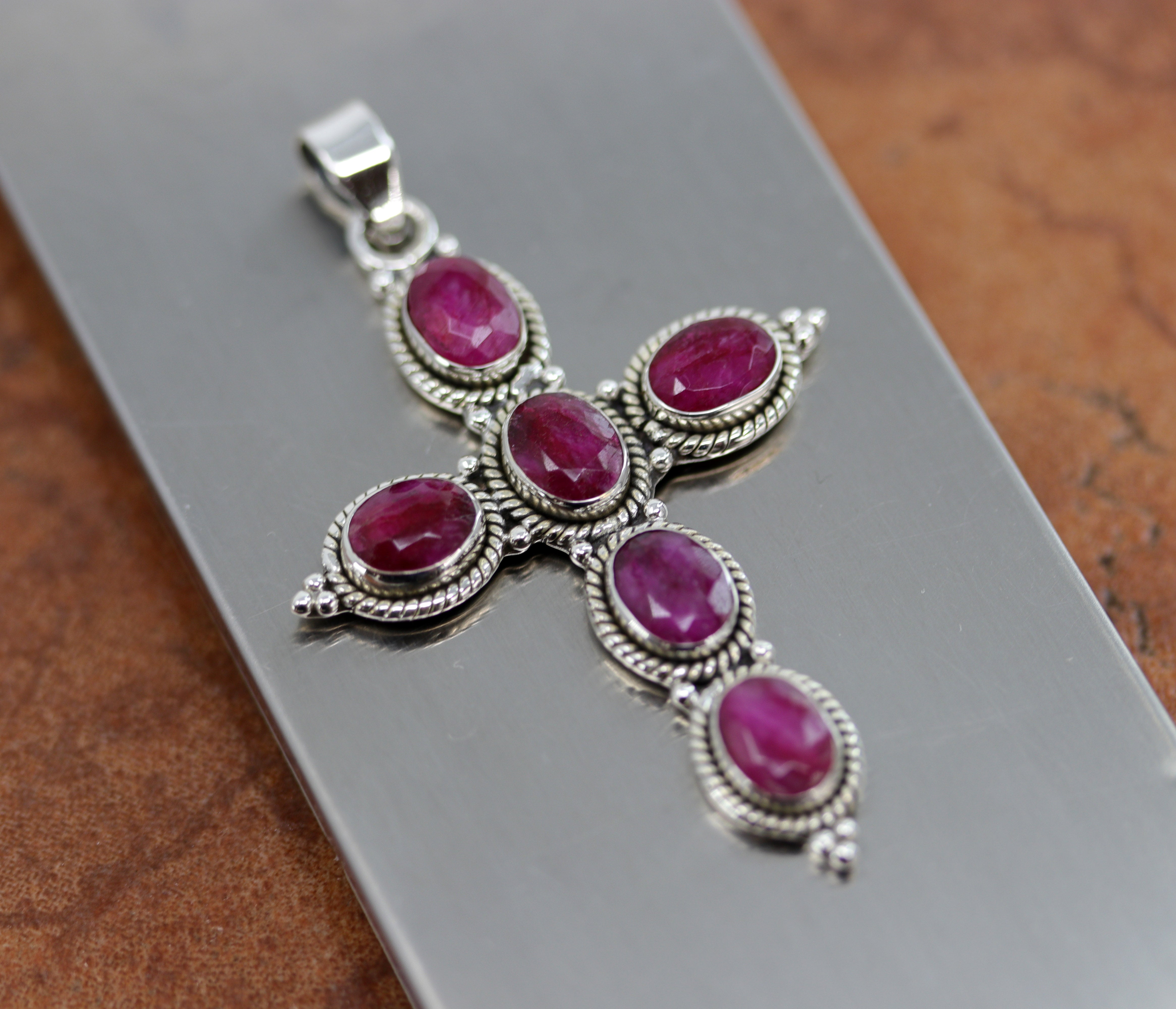 A beautiful faceted cross pendant made from Sterling Silver and ruby. It is about 2 3/8" in length including the bail, and about 1 3/8" in width.