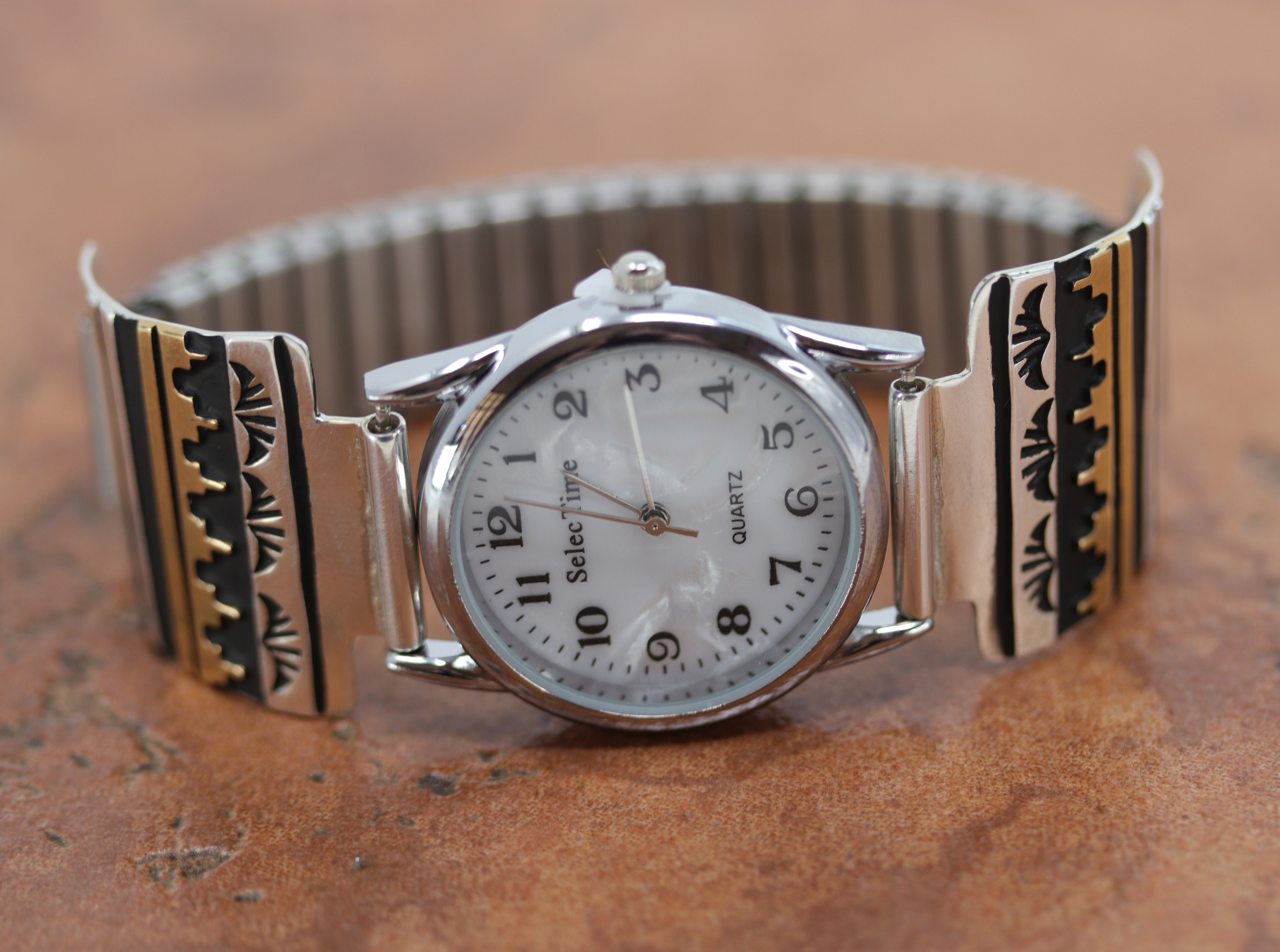 Navajo Native American watch made from sterling silver, stainless steel, and gold overlay. The Navajo designs are 1 1/2" in length, and the watch itself is about 1 1/8" in diameter.