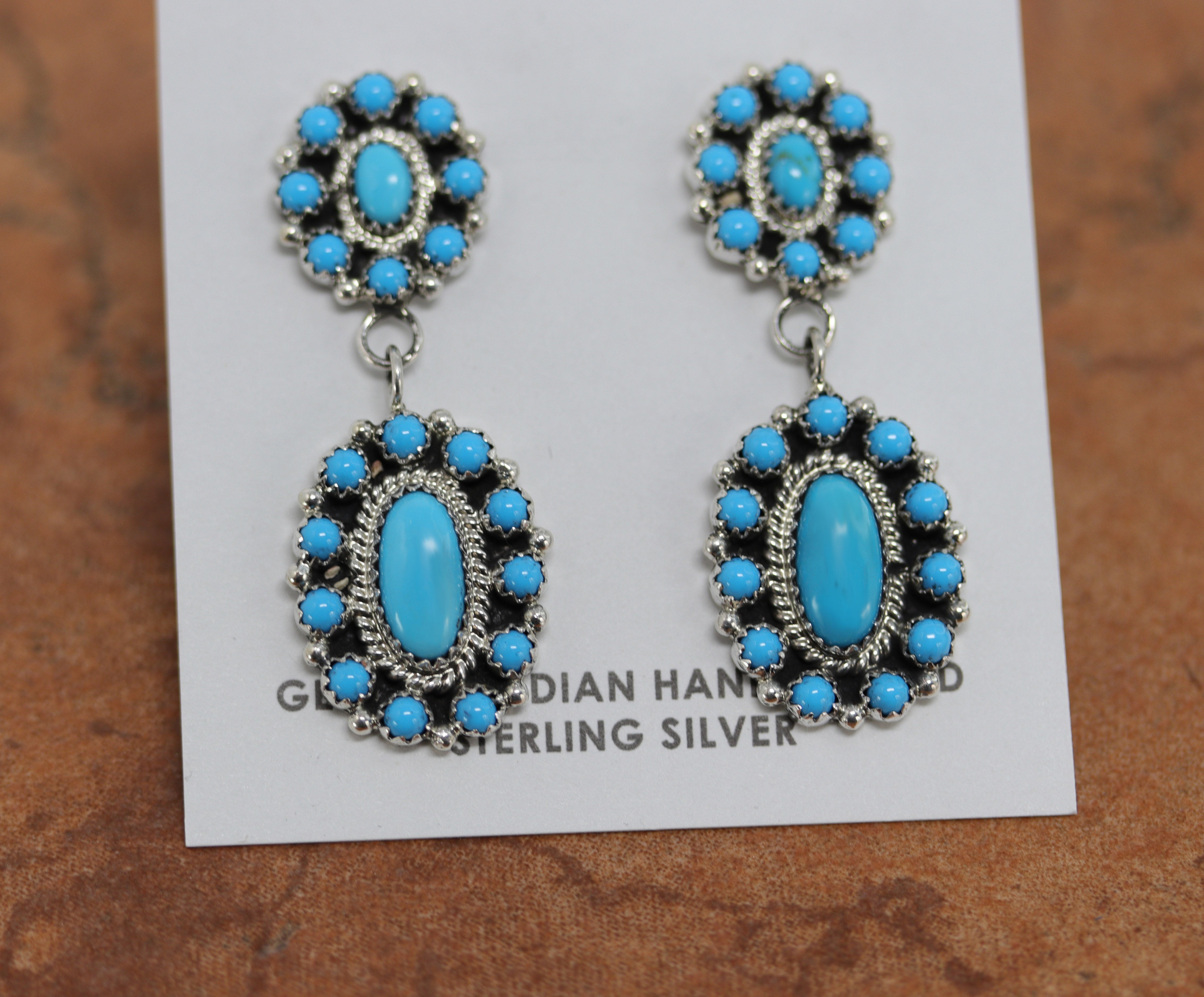 Authentic Native American cluster earrings. They are made from sterling silver and man made turquoise. The earrings are about 2" in length and 3/4" in width.