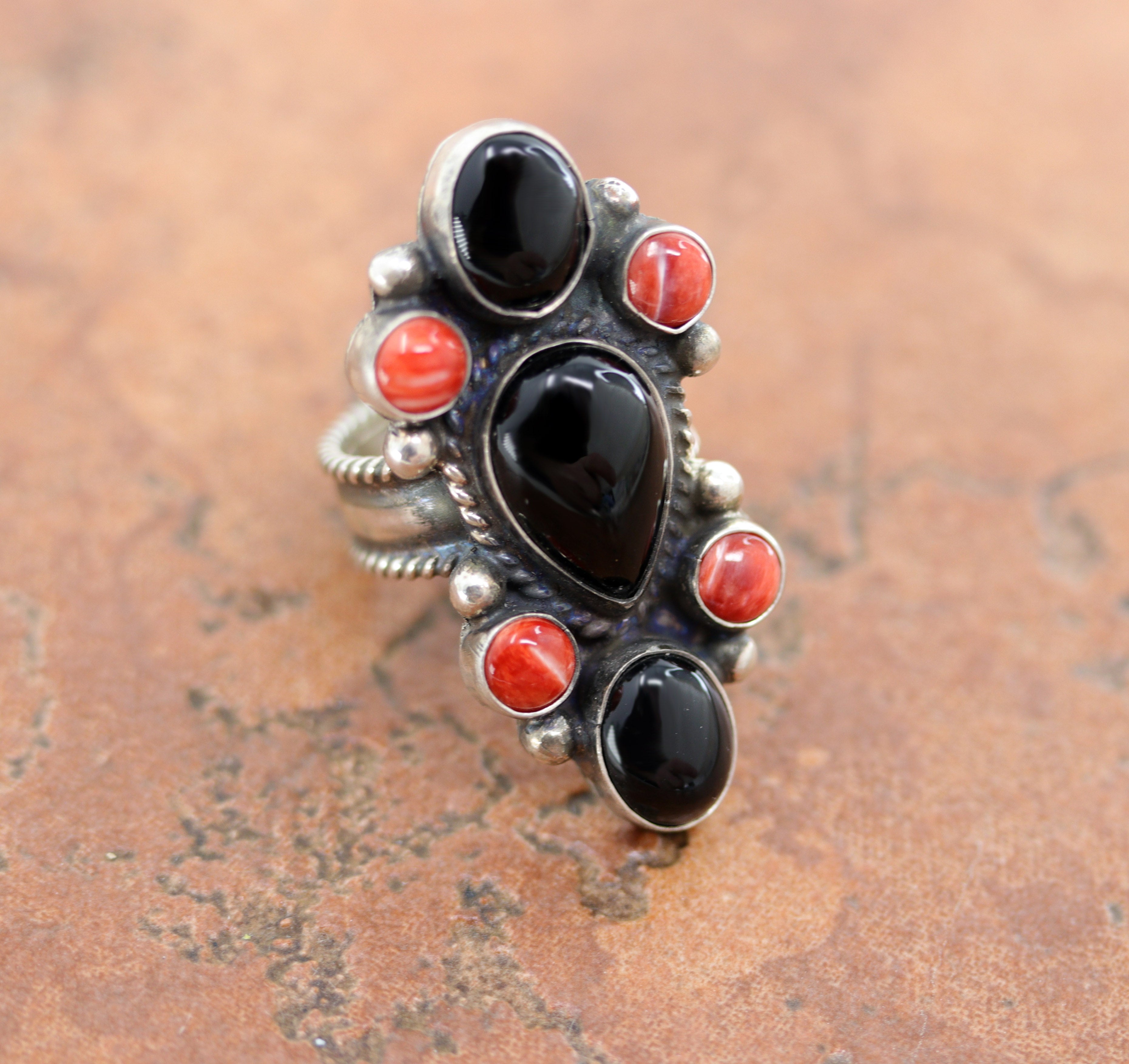 Gorgeous Navajo Native American ring. It is made from sterling silver, coral, and onyx. The ring size is adustable and fits sizes 7-9 and it is 1 5/8" in length.