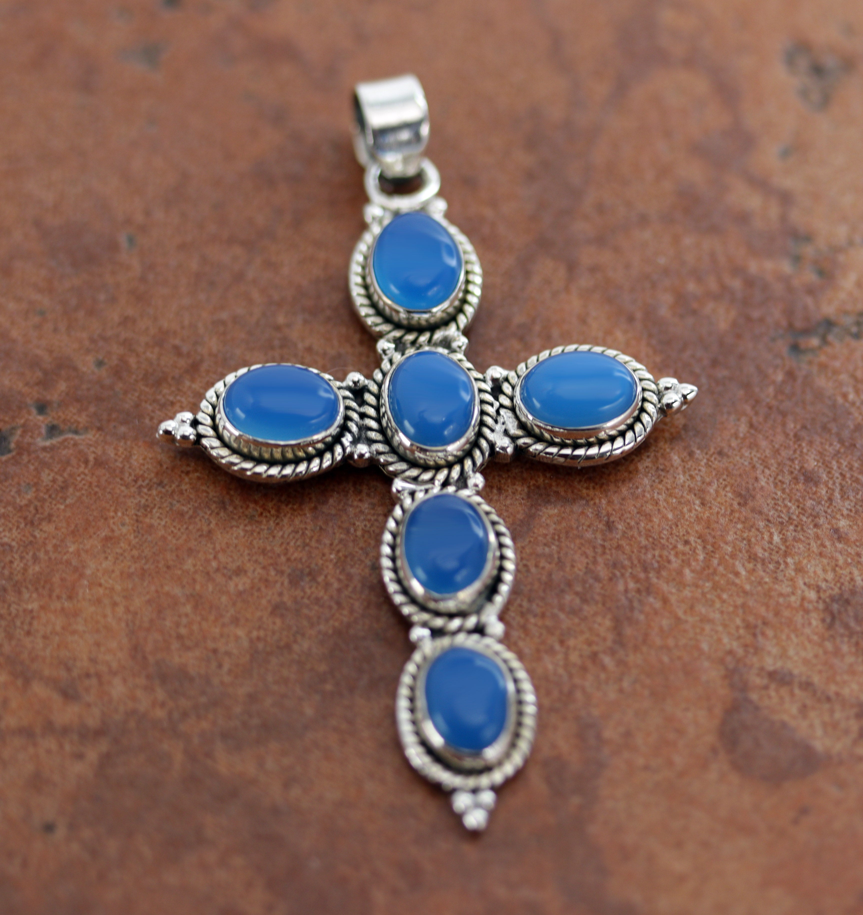 It is made from Sterling Silver and blue chalcedony. It is about 2 3/8" in length including the bail, and about 1 5/8" in width.