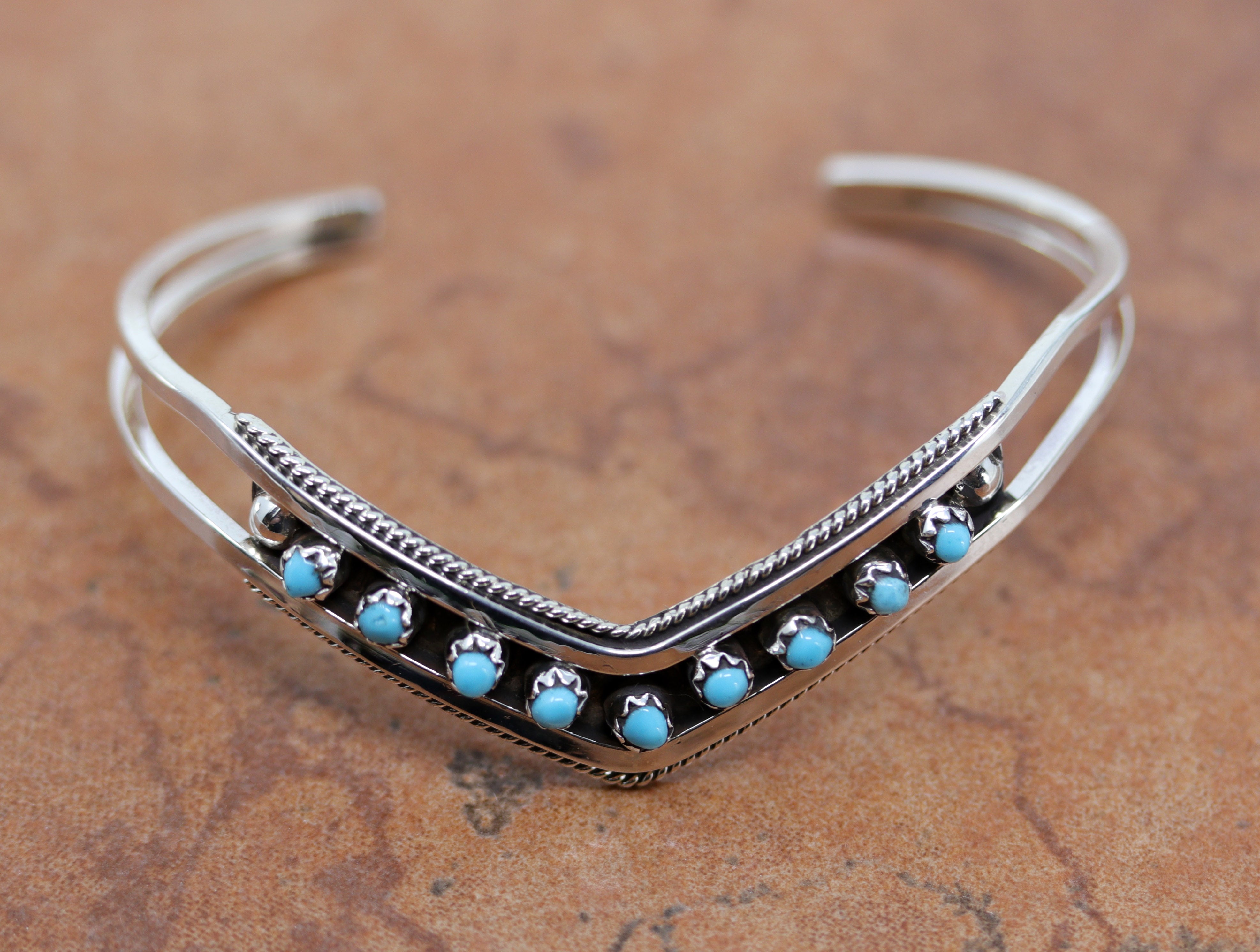 A brand new, very nice, authentic Zuni Native American bracelet. It is made from sterling silver and turquoise. It is about 5 1/4" around and about 3/8" wide at the widest point. The opening is about 1 1/4" and partly flexible.