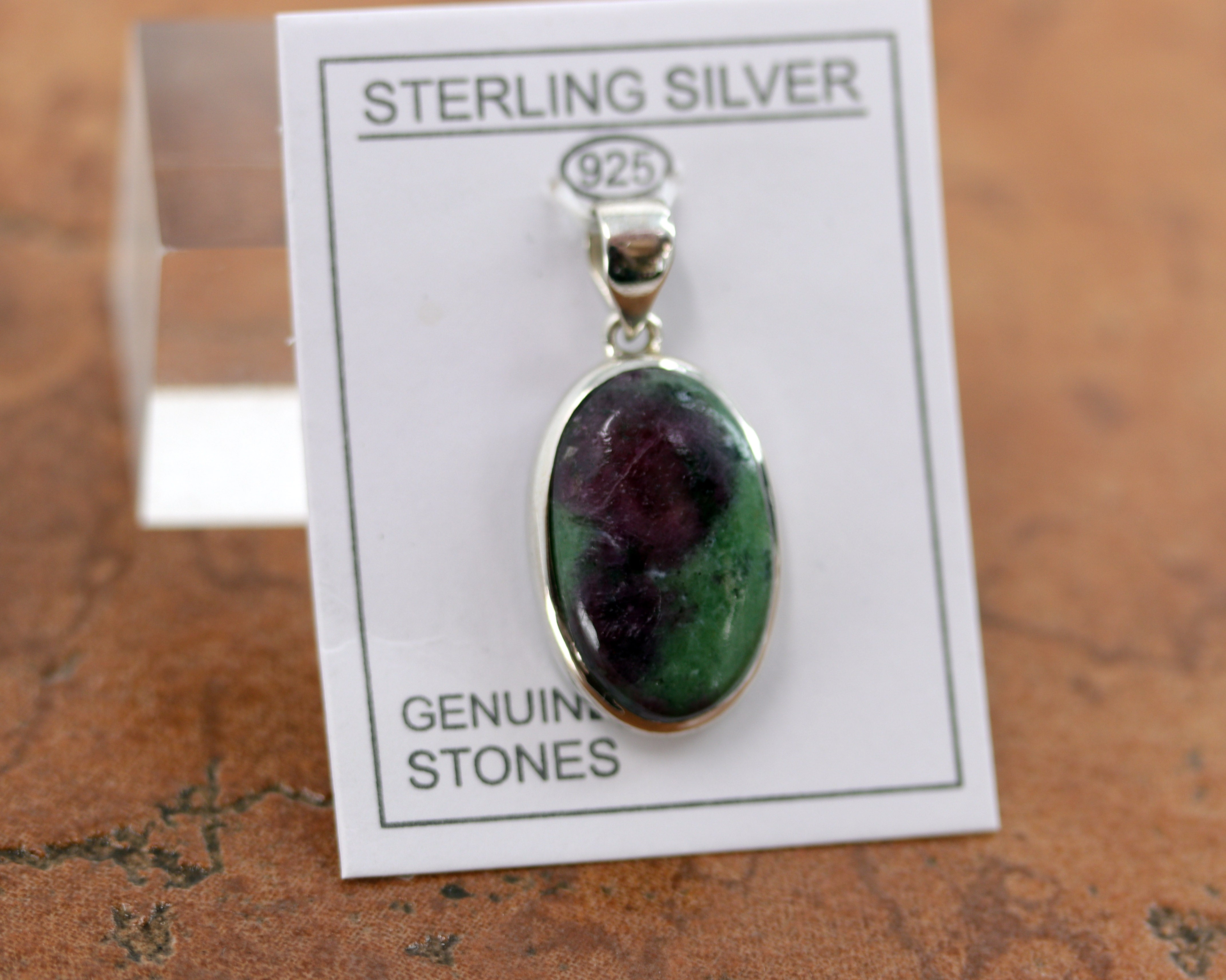 It is made from Sterling Silver and ruby zoisite. It is about 1 1/2" in length including the bail, and about 3/4" in width. 