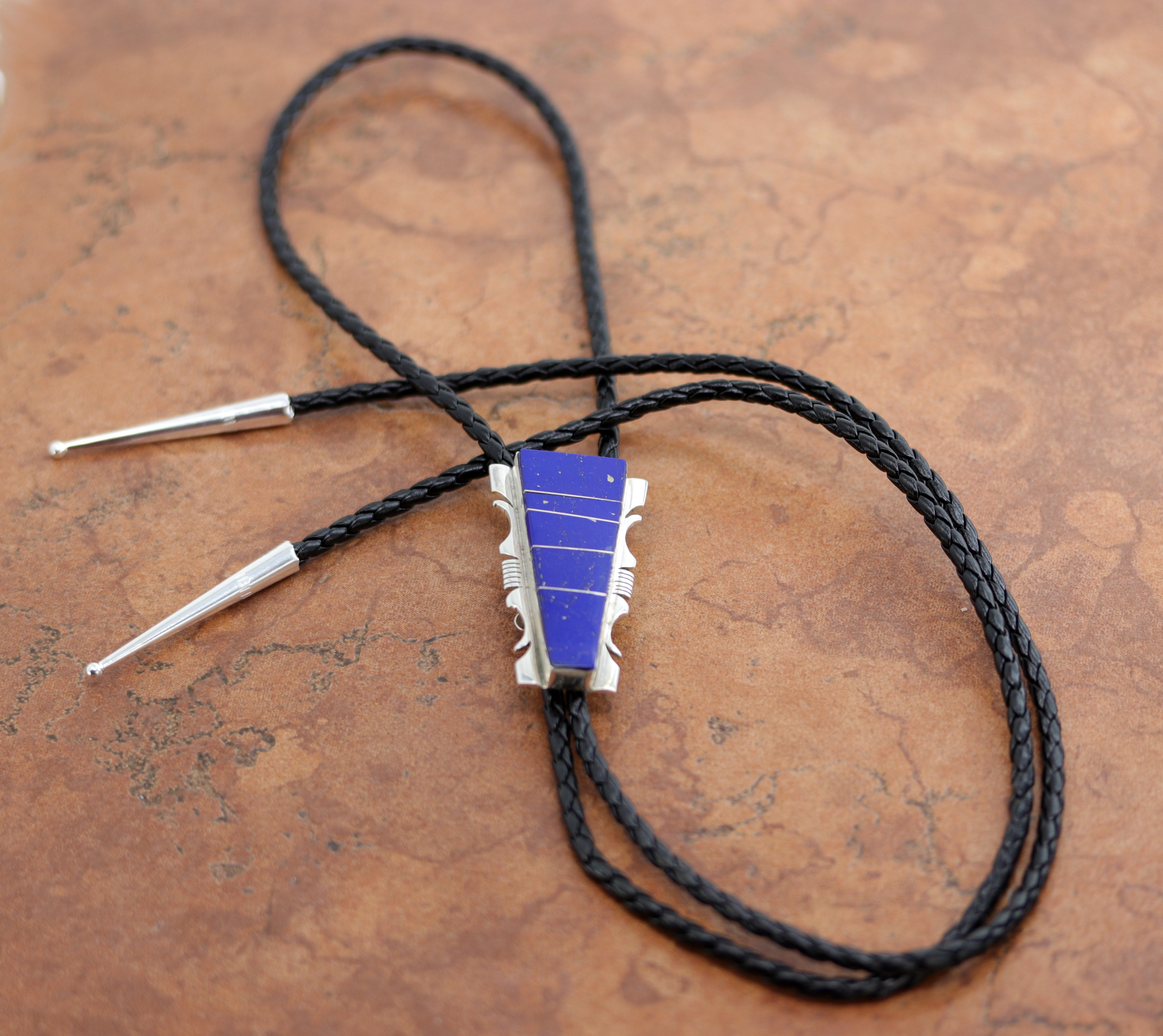 Navajo Native American Bolo Tie. The bolo tie is made of sterling silver and lapis. The cord is about 44". The bolo measures 2 1/4" by 1".