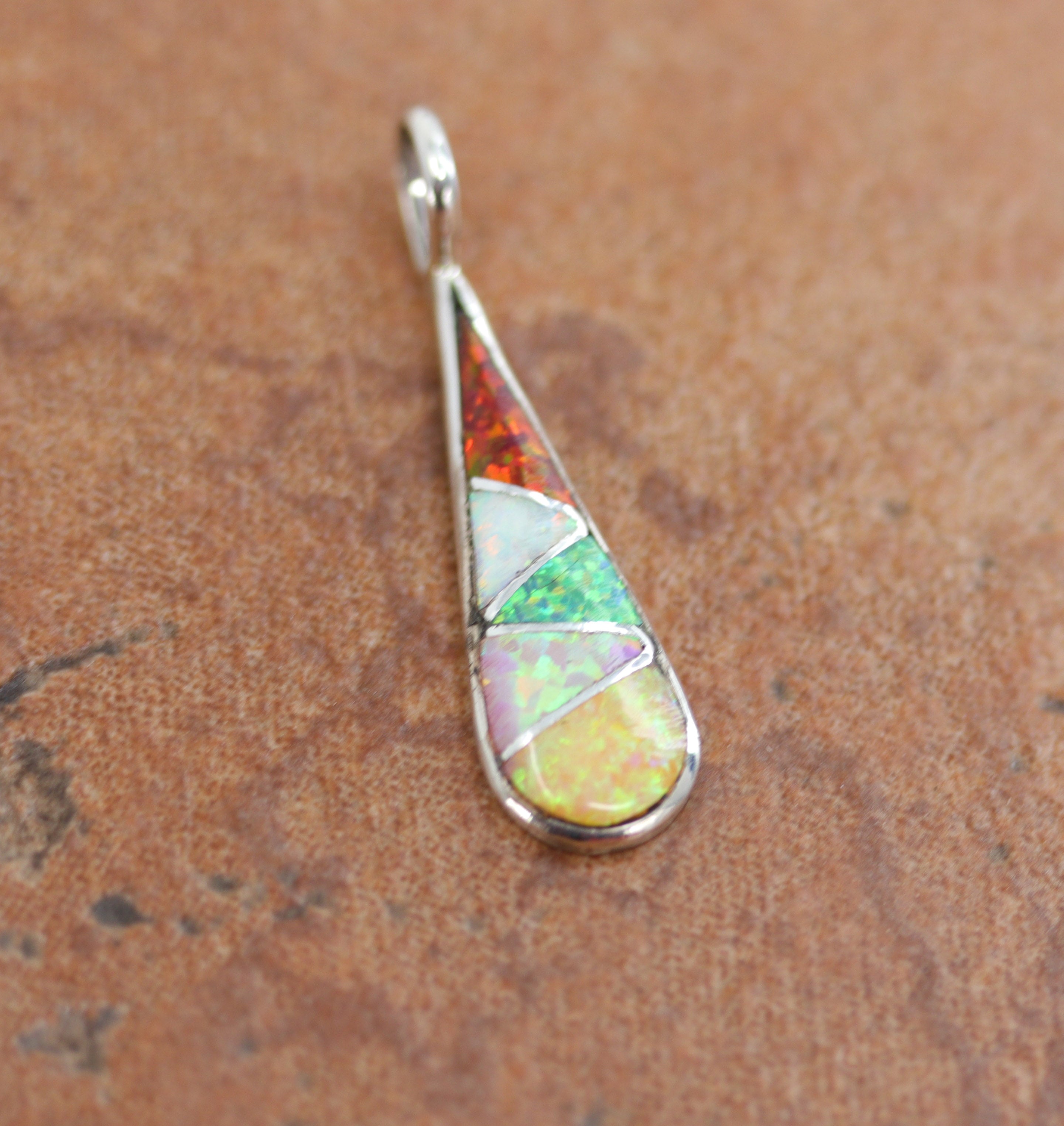 A beautiful pendant made from sterling silver and created opal. The pendant measures 1 1/4" by 3/8".&nbsp;