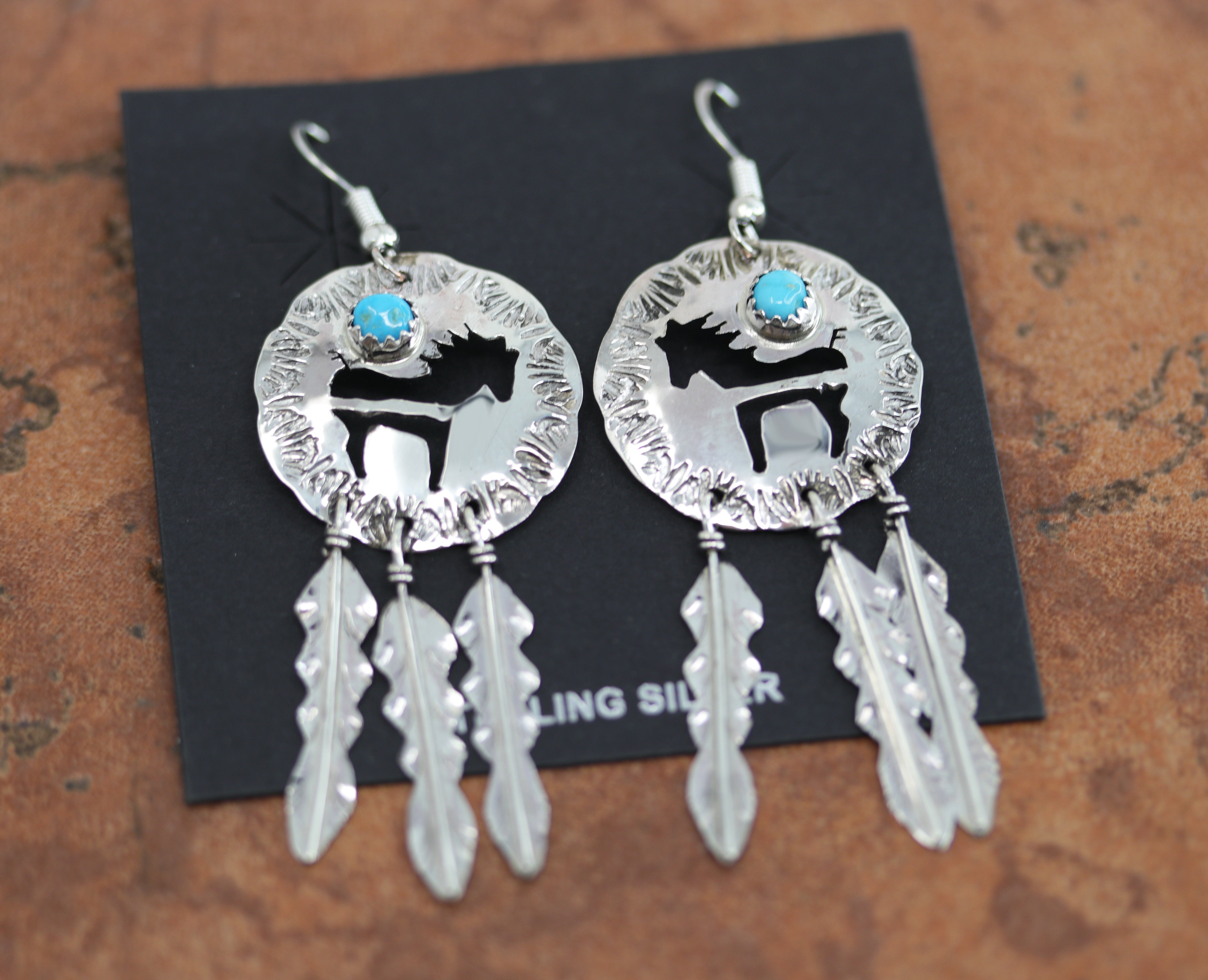 Navajo silver horse earrings. They are made from sterling silver and turquoise. Each earring is 2 5/8" in length including the hook and 1" in width.