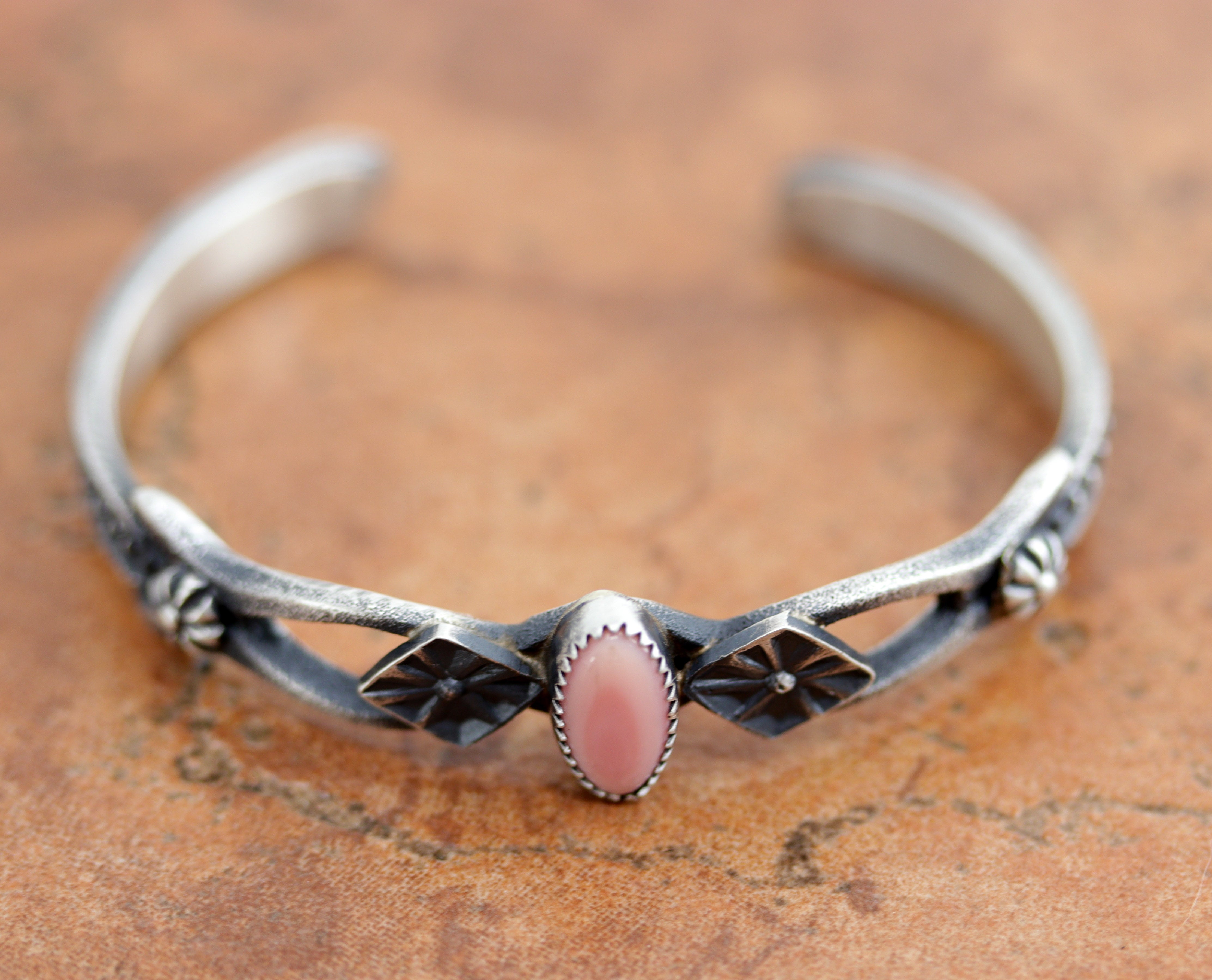 A beautiful Navajo Native American bracelet. It is made from sterling silver and pink quartz. It is about 5 1/4" around and 7/16" wide. The opening is about 1", and partly flexible.&nbsp;