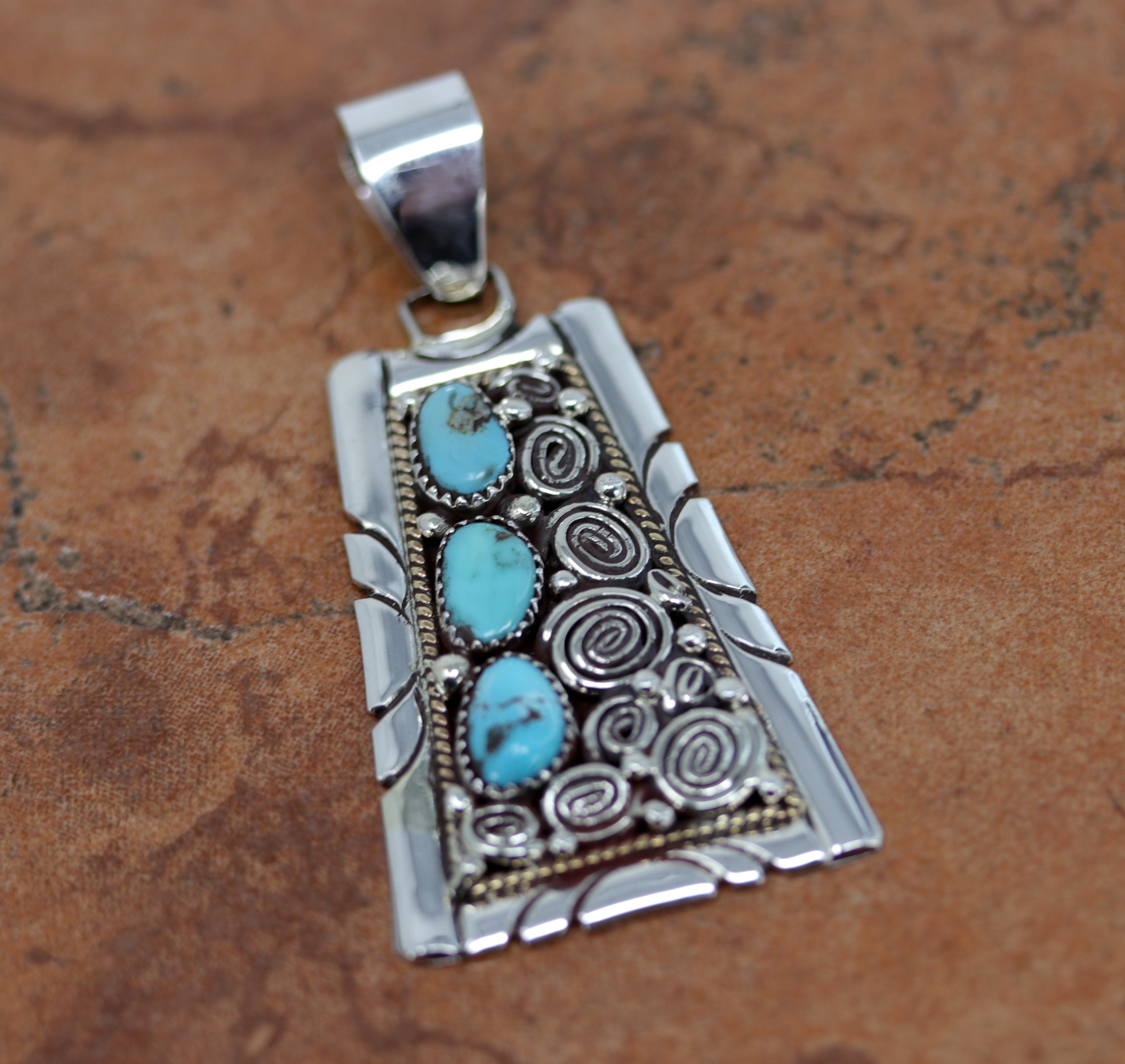 A beautiful Navajo Native American Pendant. It is made from sterling silver and turquoise. It is 1 1/2" in width and 2 7/8" in length including the bail.