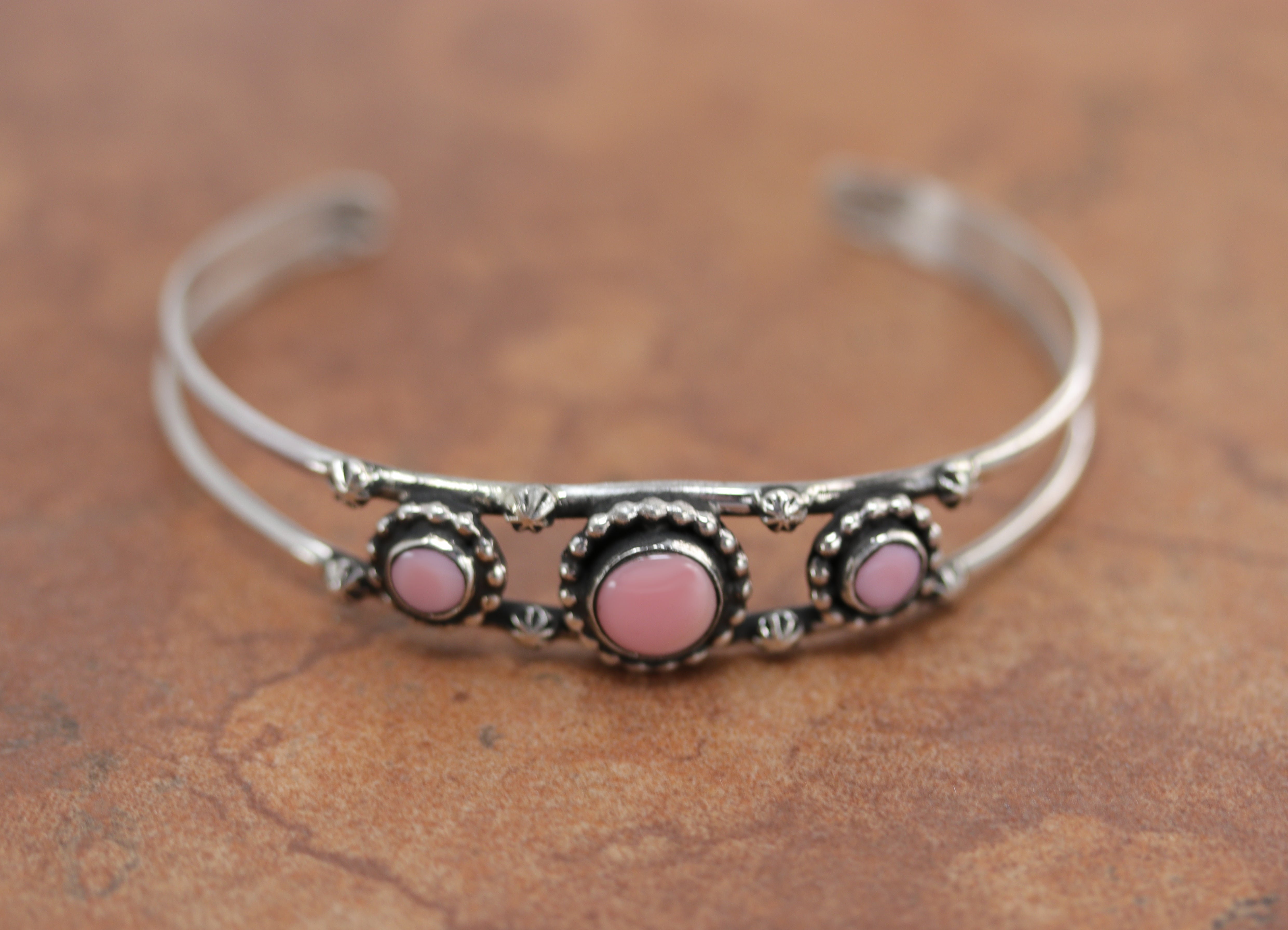 Silver cuff bracelet with three pink circular stones