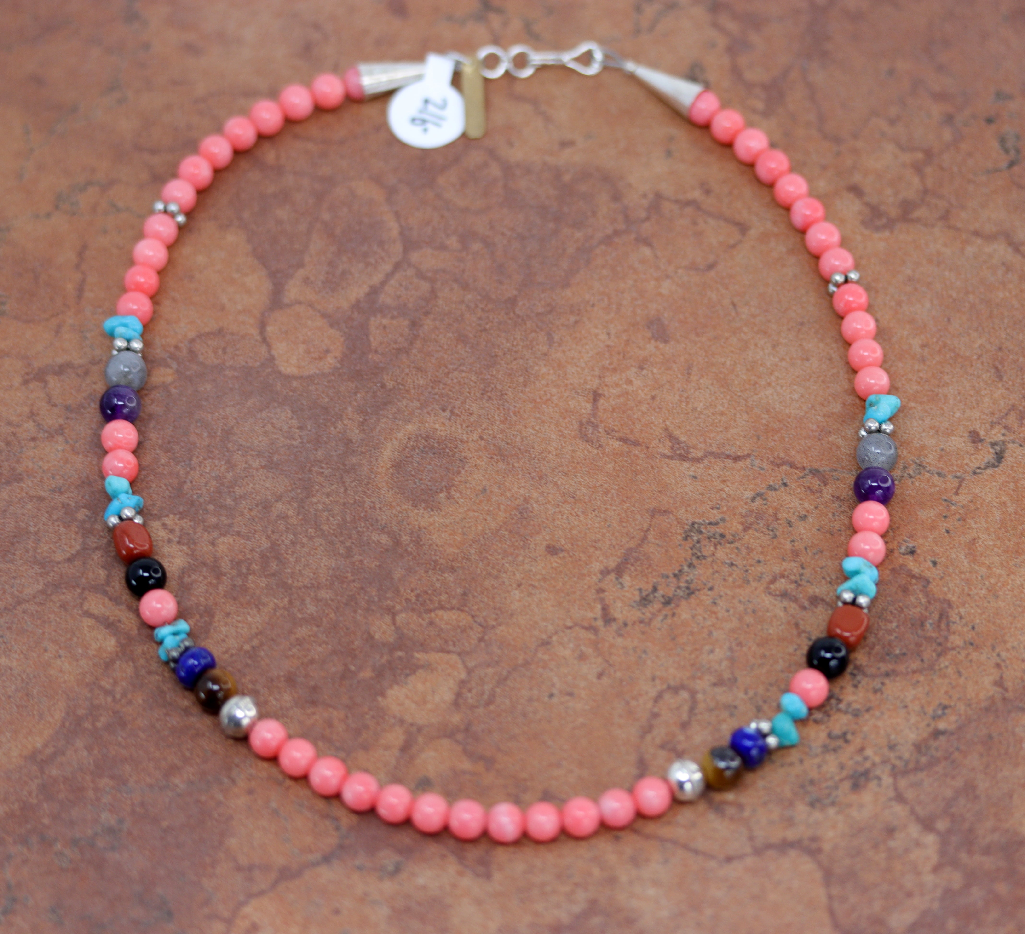 Bracelet with primarily pink beads as well as a few turqouoise, black, silver, and red beads