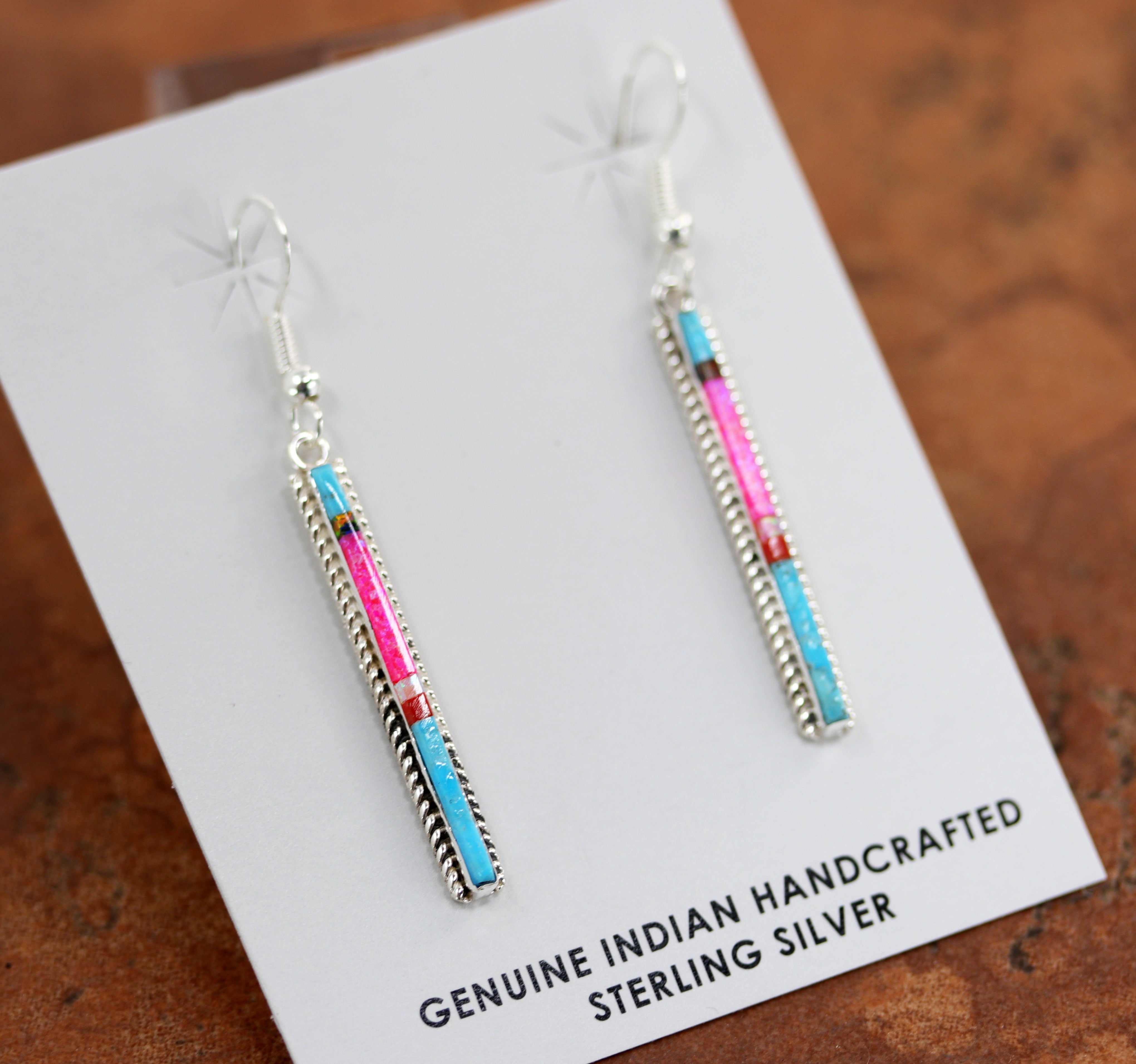 Silver rectangular earrings made with primarily pink and blue opal stones. Also has small amounts of red and white