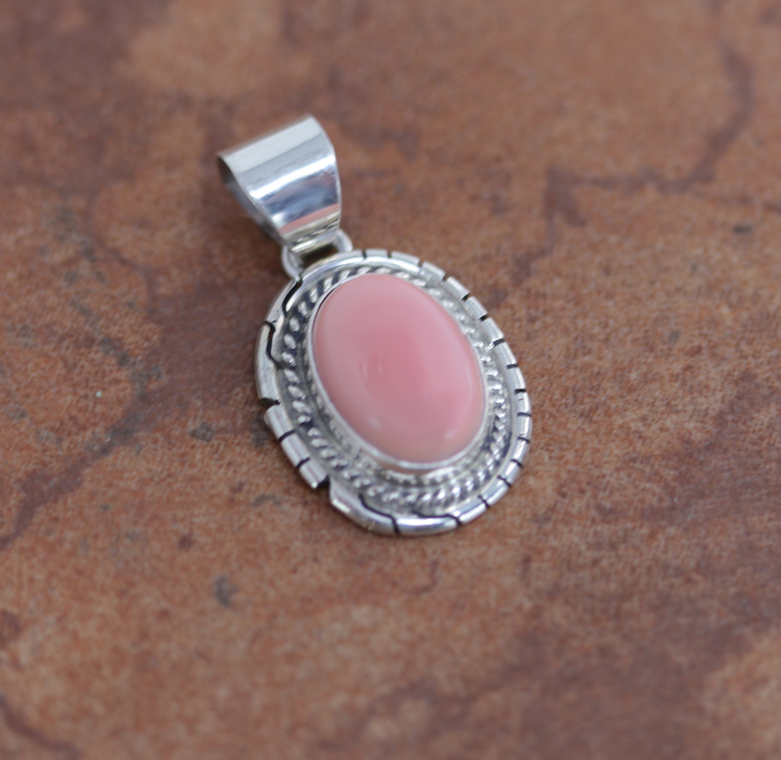 Oval shaped Silver Pendant with round pink gemstone in the middle