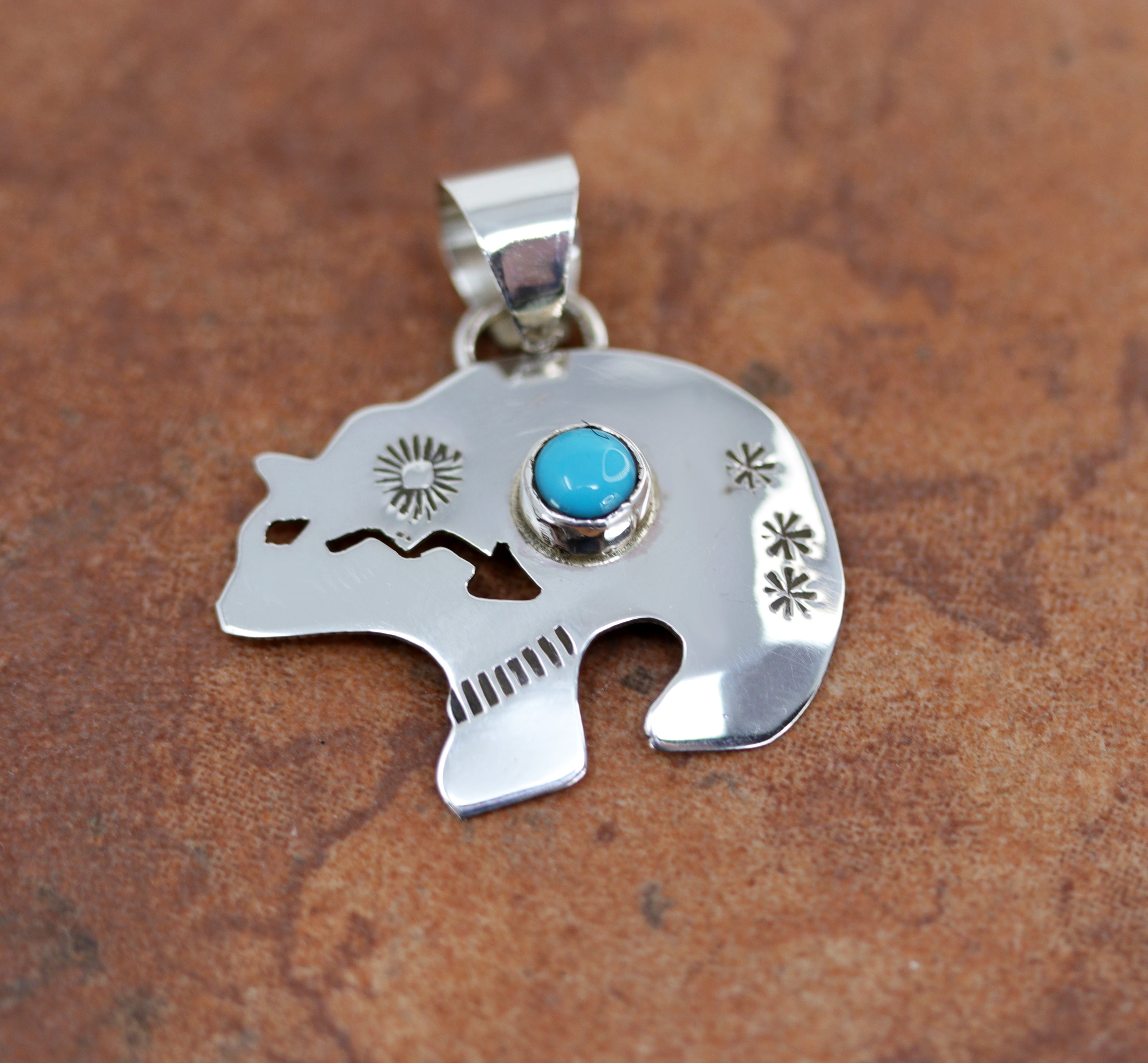 Bear shaped silver pendant with a small circular turqouoise gemstone