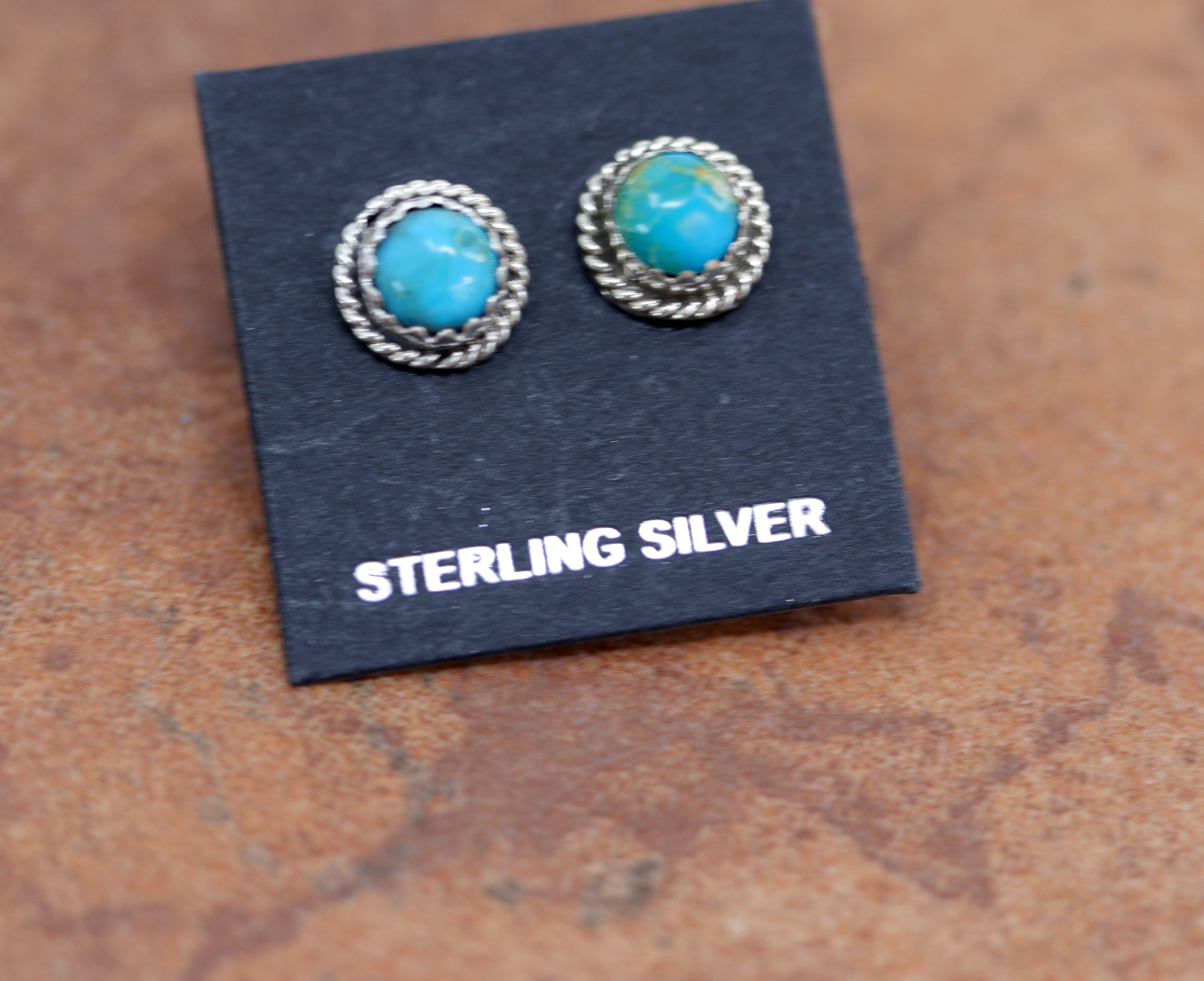 Circular silver stud earrings with round turquoise stones in the middle