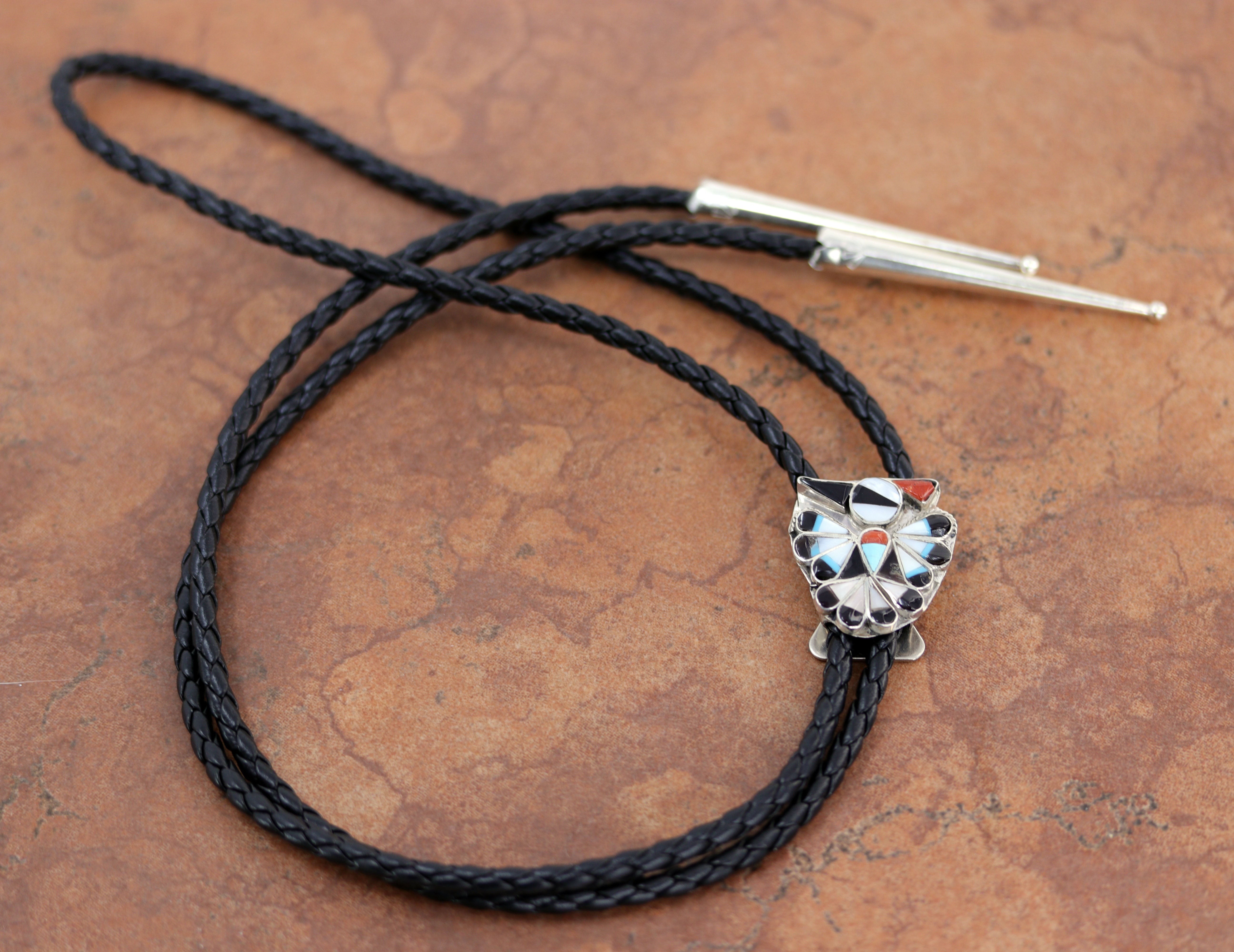 Bolo tie with black and silver cord and a bird shaped stone made of black, white, red, and turquoise stones