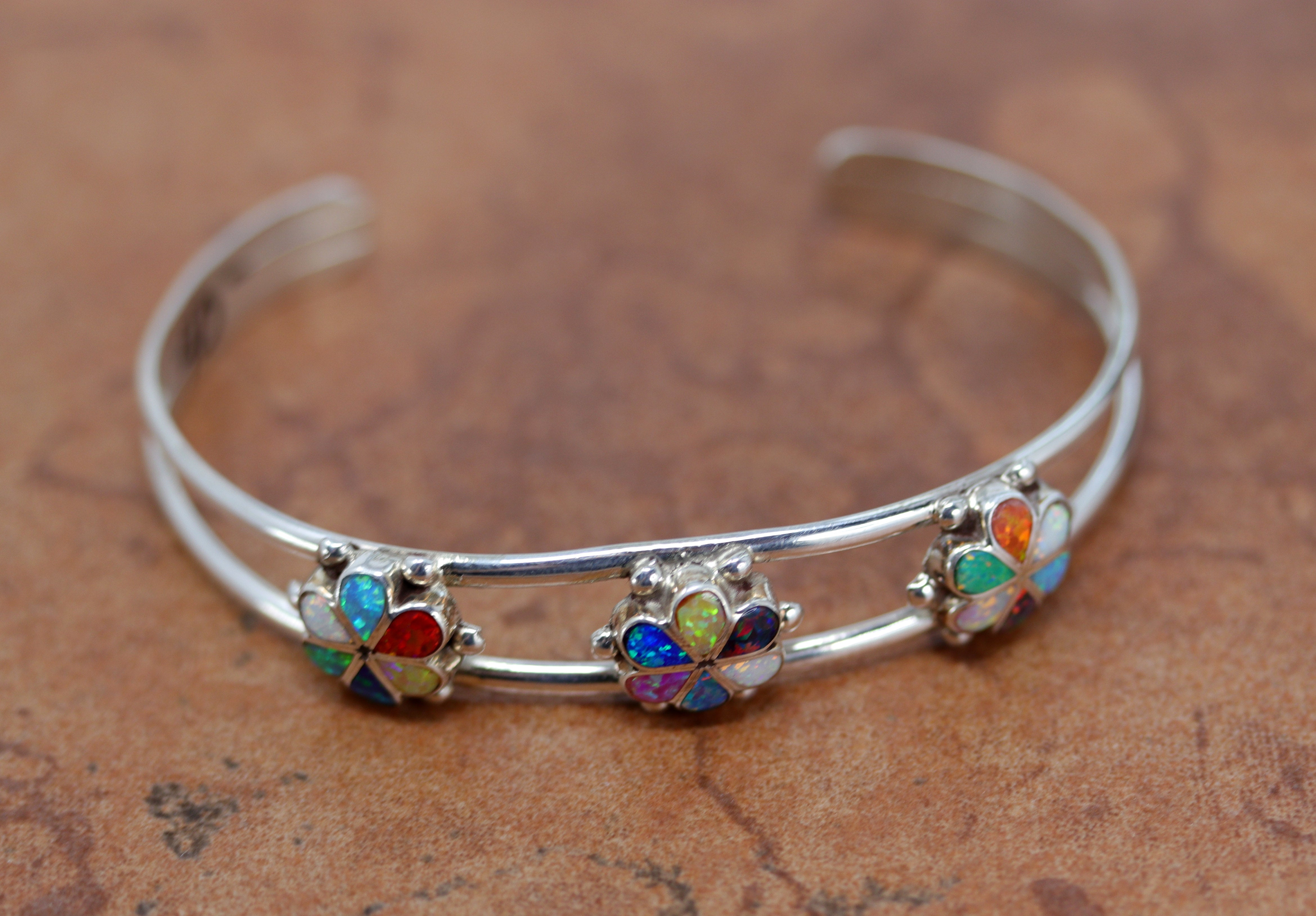 A brand new, very nice, authentic Zuni Native American flower bracelet. It is made from sterling silver and created opal. It is about 5 1/4" around and about 1/2" wide at the widest point. The opening is about 1 1/4" and partly flexible.&nbsp;